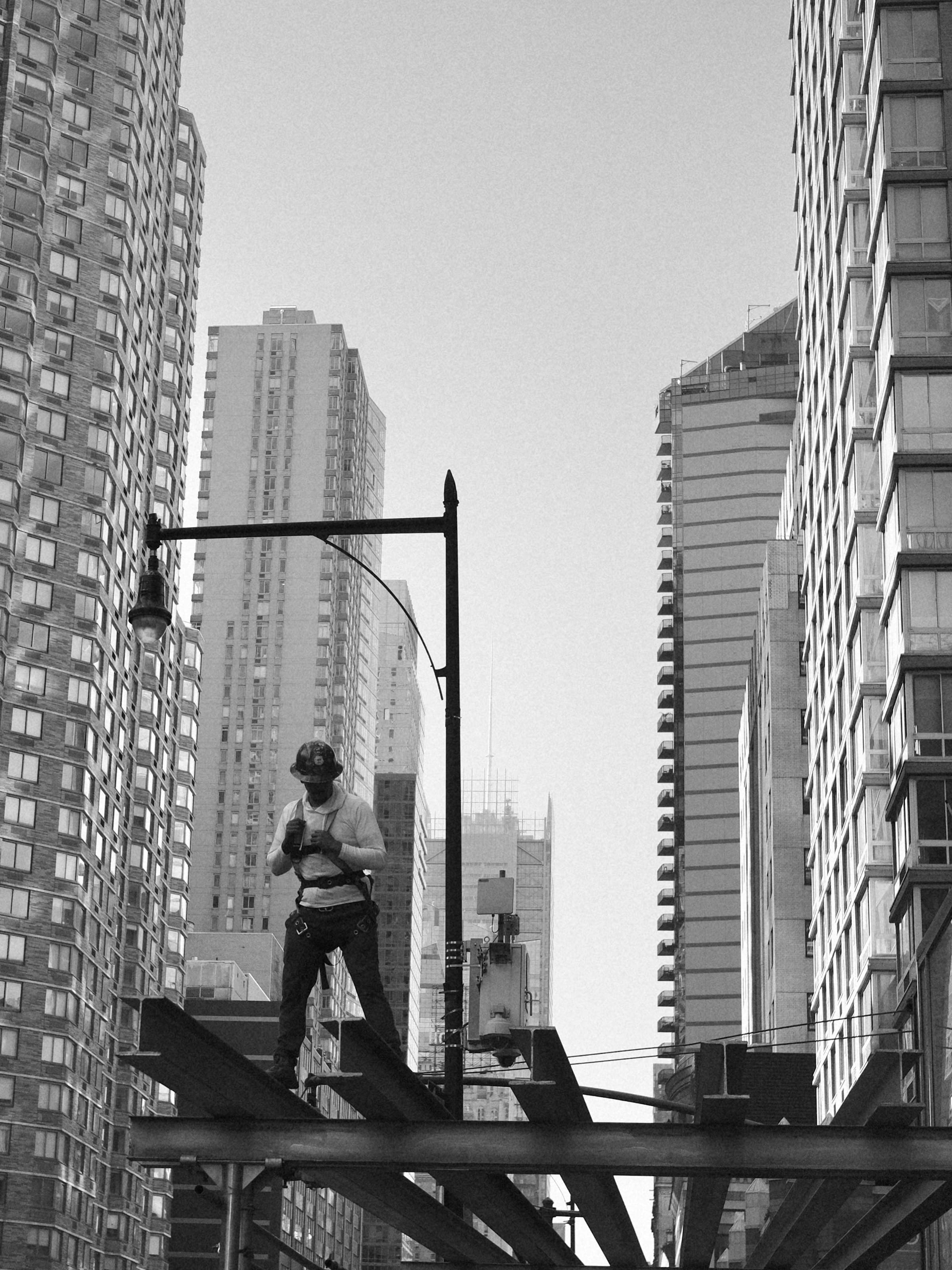 Construction worker standing on steel beams between Manhattan high-rises