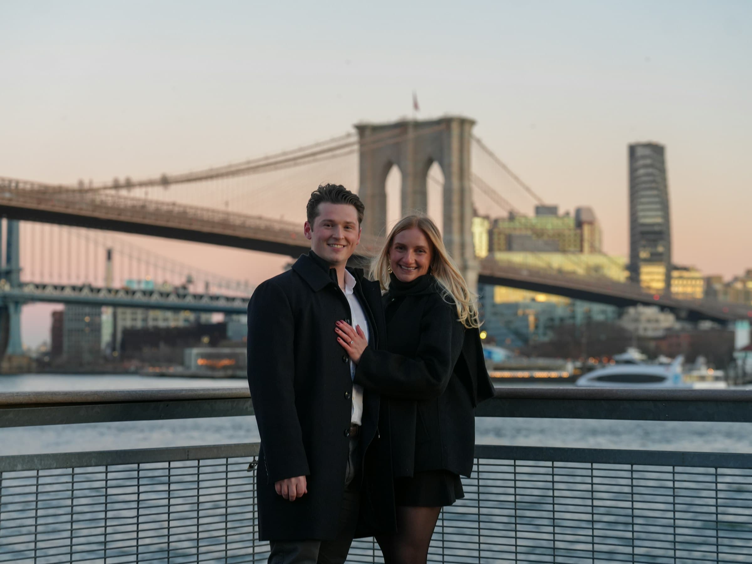 Couple embracing in front of the Brooklyn Bridge at sunset