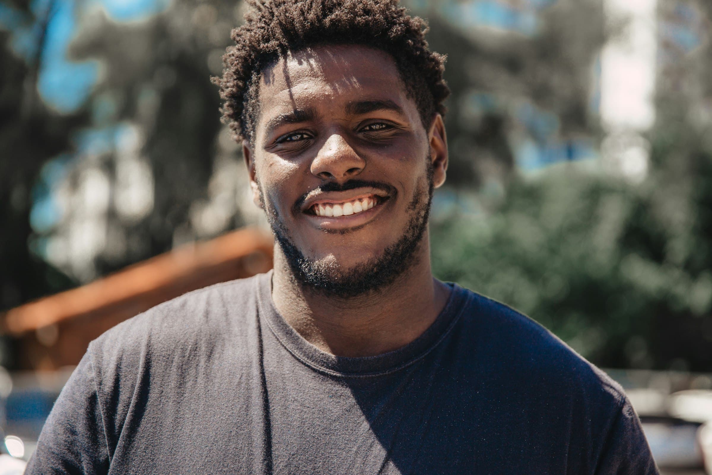 Portrait of a young man smiling warmly in natural sunlight