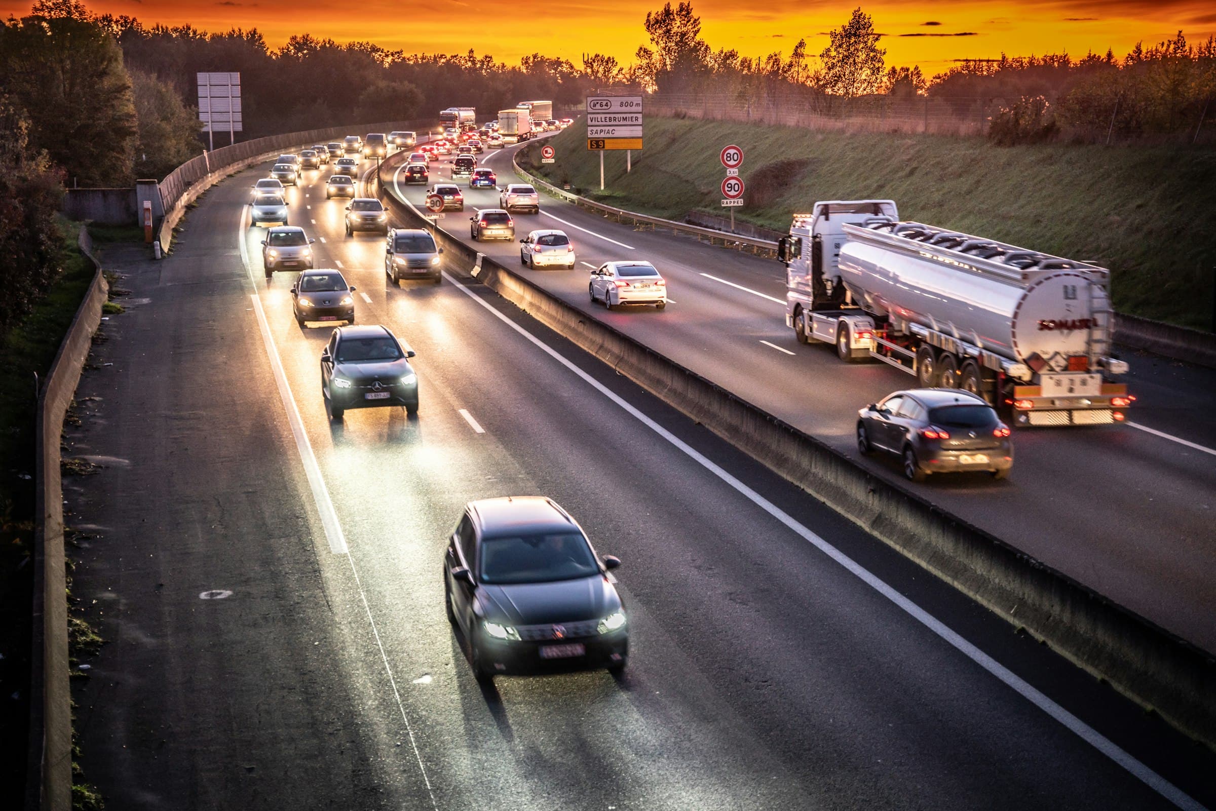 Busy highway filled with traffic at dusk under a fiery sky